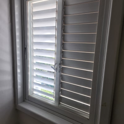 חלון עם זכוכית ותריסים לבנים