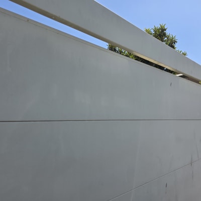 שער חשמלי לבן עם שמיים כחולים ועצים ברקע