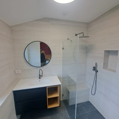 חדר אמבטיה עם מקלחון, כיור ומראה עגולה