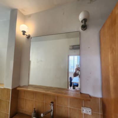 מראה עם כתמי צבע על הקיר ליד כיור