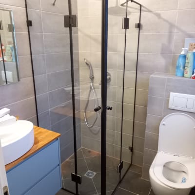 מקלחון זכוכית עם ראש מקלחת וכיור לידו