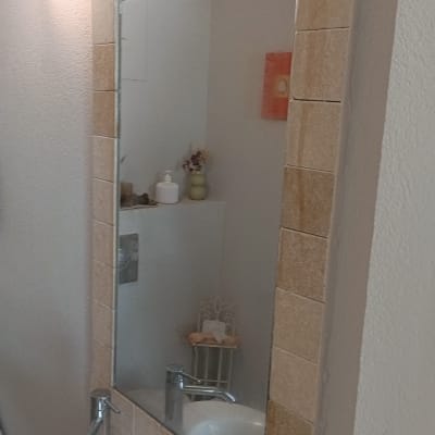 מראה עם מסגרת אריחים מעל כיור בחדר אמבטיה