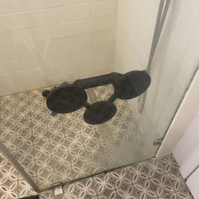 מקלחון עם רצפת אריחים ודלת זכוכית