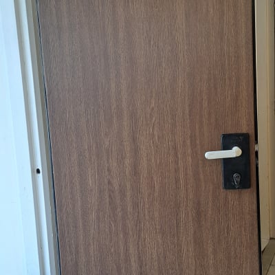 דלת עץ עם ידית מתכת כסופה ומנעול שחור