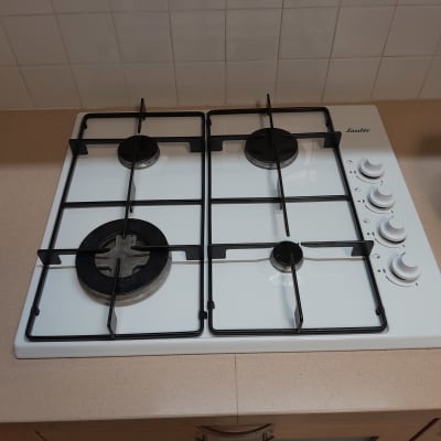 כיריים גז לבנות עם ארבעה מבערים וכפתורי שליטה