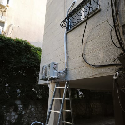 מזגן מותקן על קיר חיצוני עם סולם