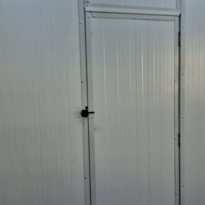 דלת מתכת לבנה עם מנעול בגינה