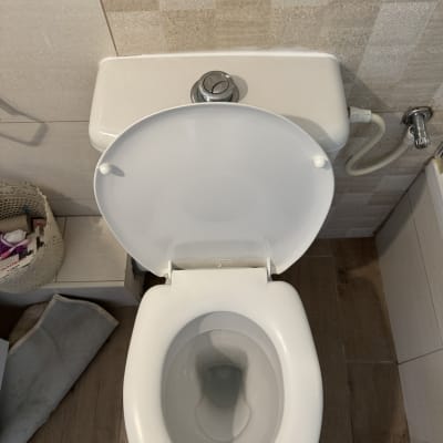 אסלה פתוחה עם מיכל הדחה וצינור מים