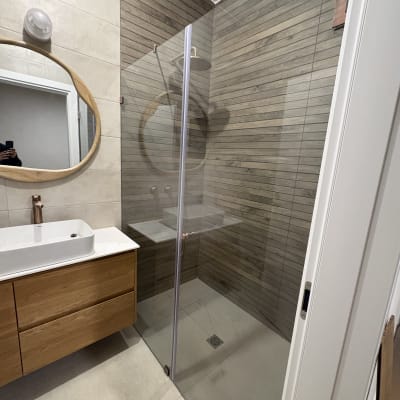 מקלחון זכוכית עם קיר עץ וכיור עץ בחדר אמבטיה מודרני