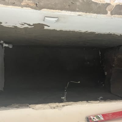 קיר עם טיח מתקלף, נורה חשופה ומוט מדידה אדום