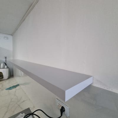 מדף עץ מותקן על קיר עם שקע חשמל