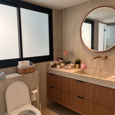 חדר אמבטיה עם כיור, מראה עגולה ומוצרי טיפוח על השיש