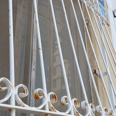 סורגי מתכת לבנים עם חלודה קלה על חלון