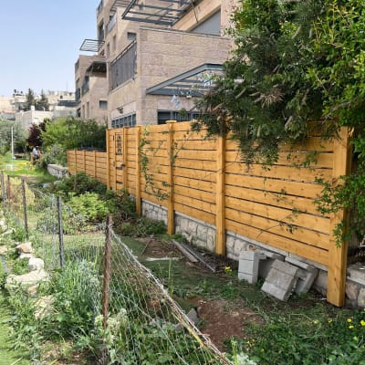 גדר עץ בגינה עם צמחים ובלוקים