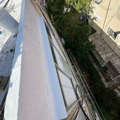 איטום גג עם חומר לבן ליד חלון בניין