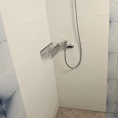 מקלחת חדשה עם אריחים, ראש מקלחת ומדף מתכת