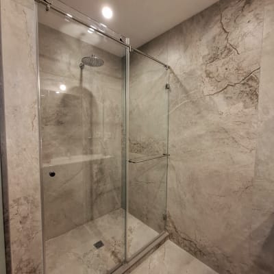 מקלחת עם דלת זכוכית וראש גשם
