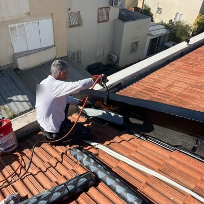 אדם עובד על גג עם כלים לאיטום