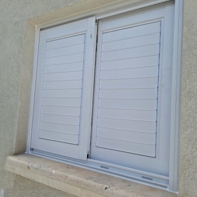 תריסי אלומיניום לבנים בחלון קיר חיצוני