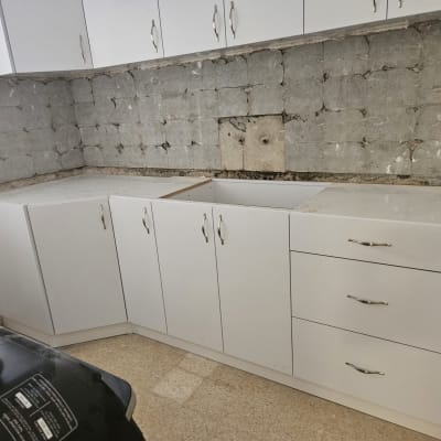 ארונות מטבח לבנים מותקנים על קיר ללא חיפוי