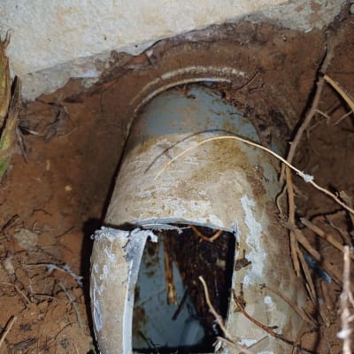 צינור שבור באדמה עם לכלוך וענפים