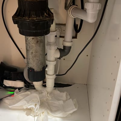 צנרת מתחת לכיור עם ניירות סופגים על הרצפה