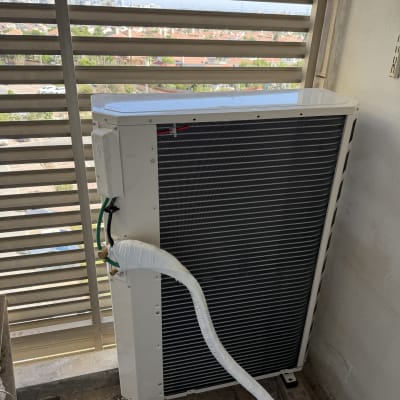 יחידת מיזוג אוויר מותקנת במרפסת עם נוף עירוני ברקע.