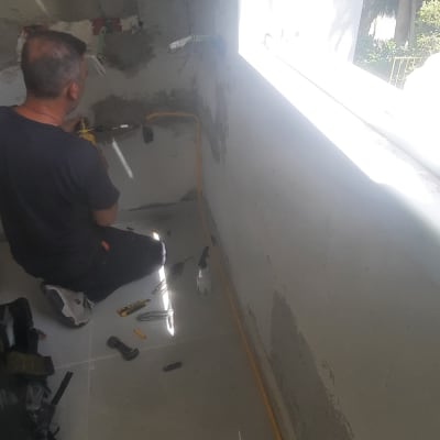 אדם עובד על קיר עם כלים וחוטי גז