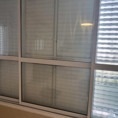 חלון זכוכית עם תריסים סגורים ושרפרף לבן על הרצפה