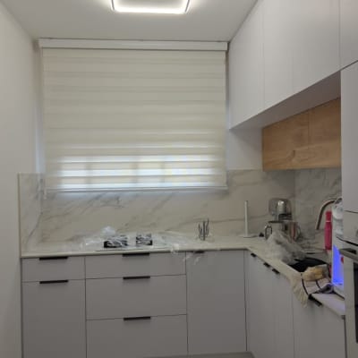 וילון גלילה במטבח מודרני עם ארונות לבנים ותאורה מעוצבת