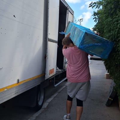 אדם נושא קופסה גדולה למשאית פתוחה