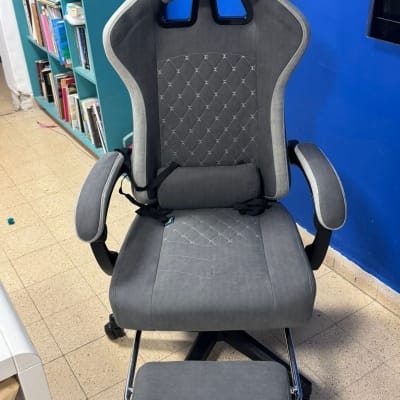כיסא משרדי אפור עם משענת רגליים בחדר עם מדפים