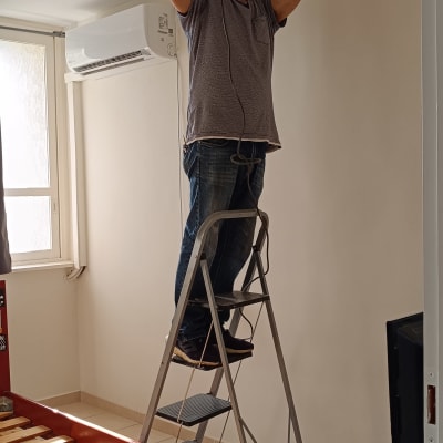 אדם על סולם קודח בתקרה עם מקדחה חשמלית