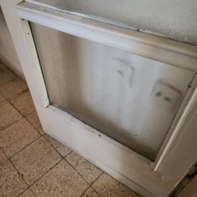 זכוכית מטושטשת עם סימני ידיים על דלת עץ