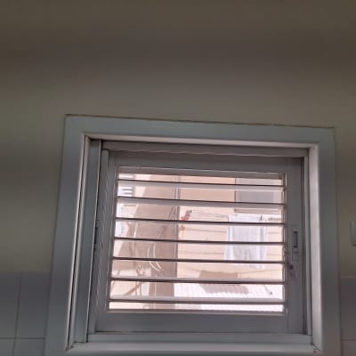 חלון עם תריסים פתוחים, קיר לבן ושקע חשמל