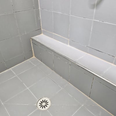 מקלחת עם אריחים אפורים וניקוז ברצפה