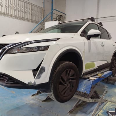 רכב לבן על מעלית עם תיקוני צבע בצד