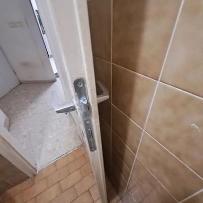 דלת פתוחה עם ידית מתכת ורצפת אריחים חומים