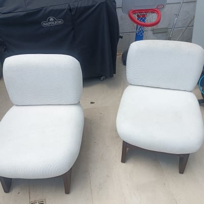 שני כיסאות לבנים על רצפת אבן ליד ציוד ניקוי