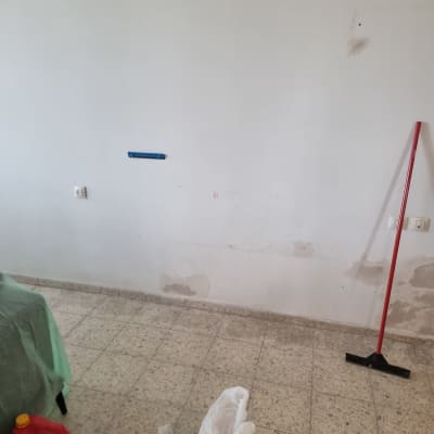 קיר עם סימני תיקון וכלי עבודה לצביעה