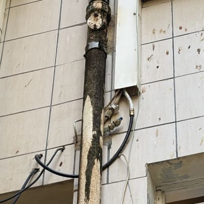צנרת מערכת סולארית וסימני נזילה על קיר חיצוני של בניין