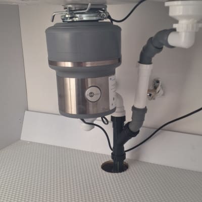 מתקן טוחן אשפה מתחת לכיור עם צינורות חיבור