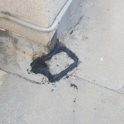 אזור אטום בזפת שחורה על רצפה ליד קיר