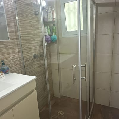 מקלחון זכוכית עם מוצרי טיפוח ומגבות רחצה