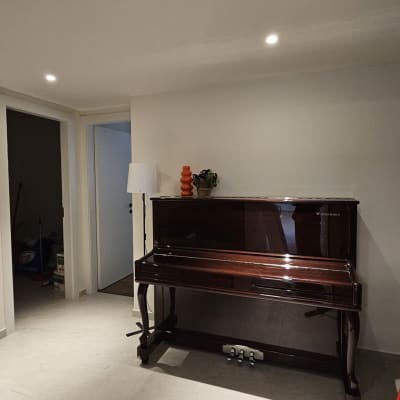 פסנתר עומד בחדר עם רצפת אריחים, מטאטא בצד