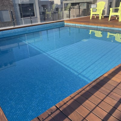 בריכת שחייה עם דק עץ וכיסאות ירוקים