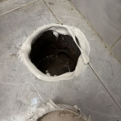 חור ברצפה עם חומר איטום לבן סביבו