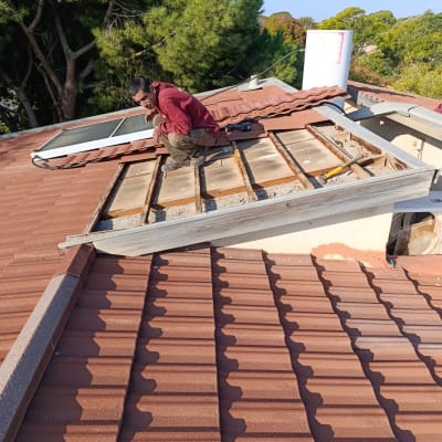 אדם עובד על גג רעפים עם כלי עבודה