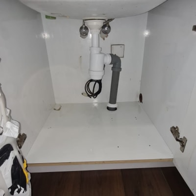 צנרת מתחת לכיור עם ברזים וצינור פלסטיק