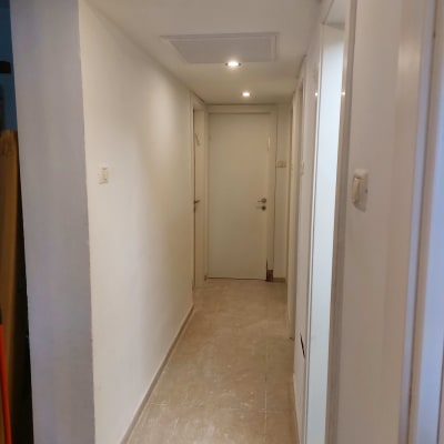 מסדרון עם קירות לבנים ודלתות, תאורה עליונה